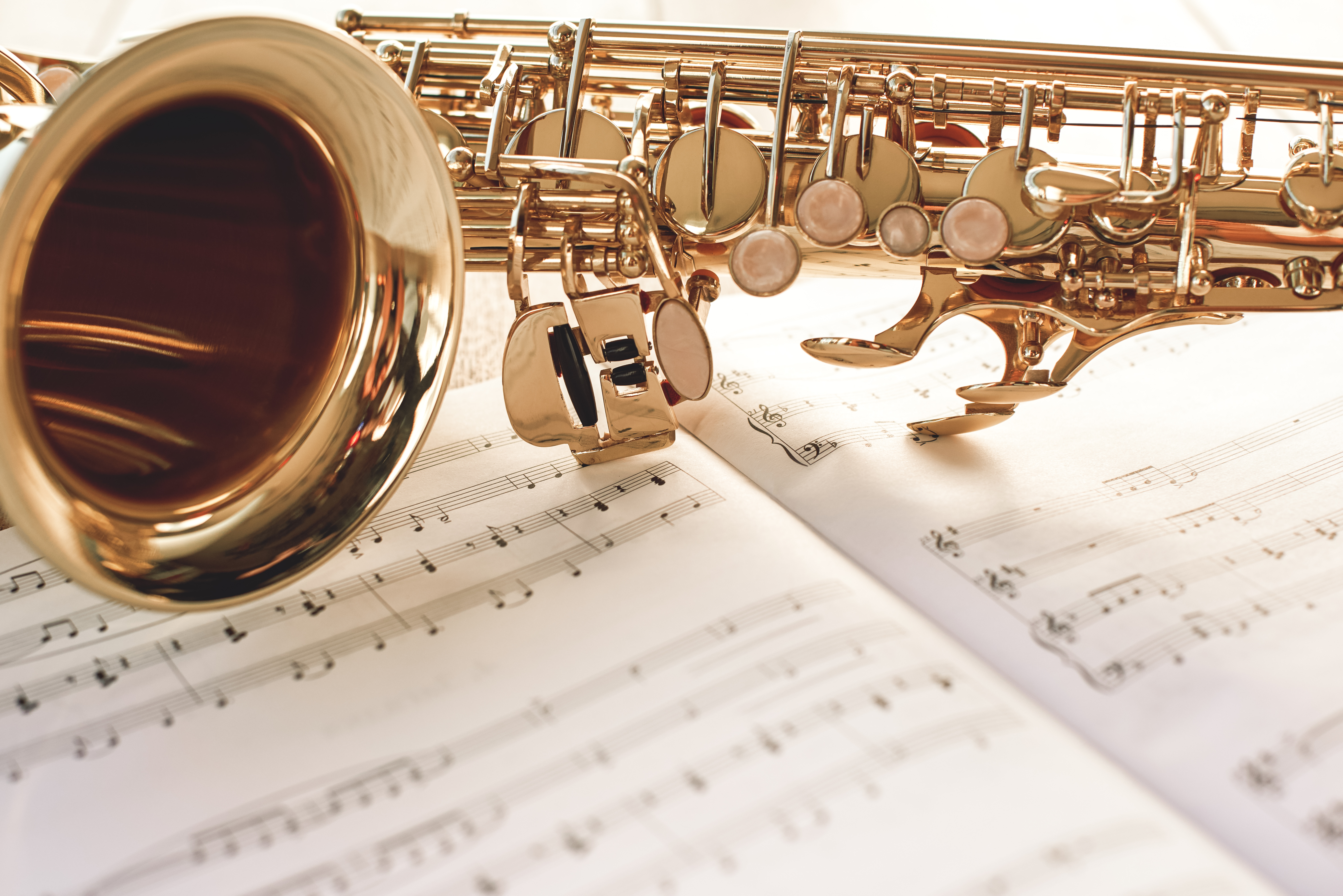 Nærbilde av en gyllen saksofon liggende på musikknoter