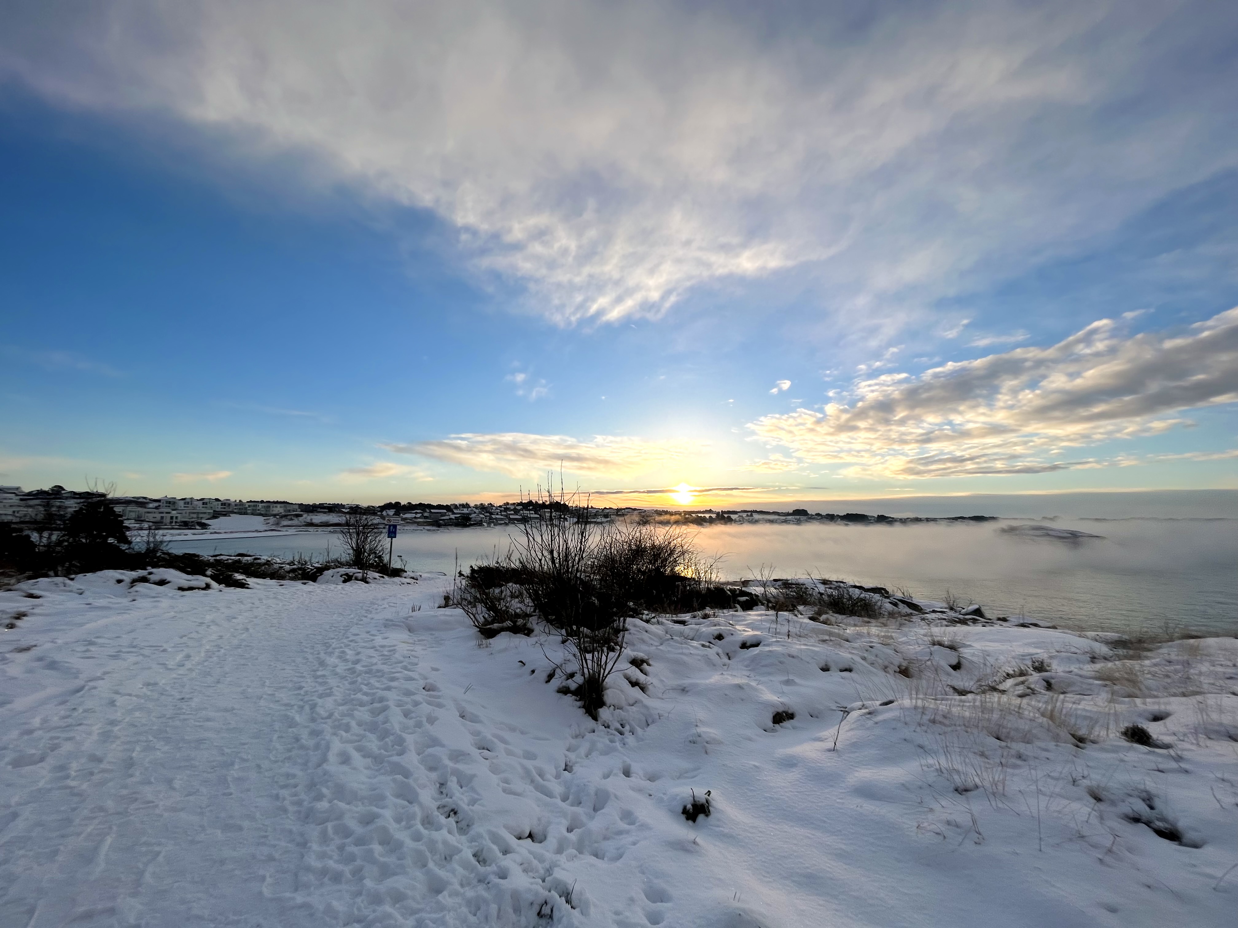 vinterlandskap, strand, horisont med blå himmel, sol, skyer