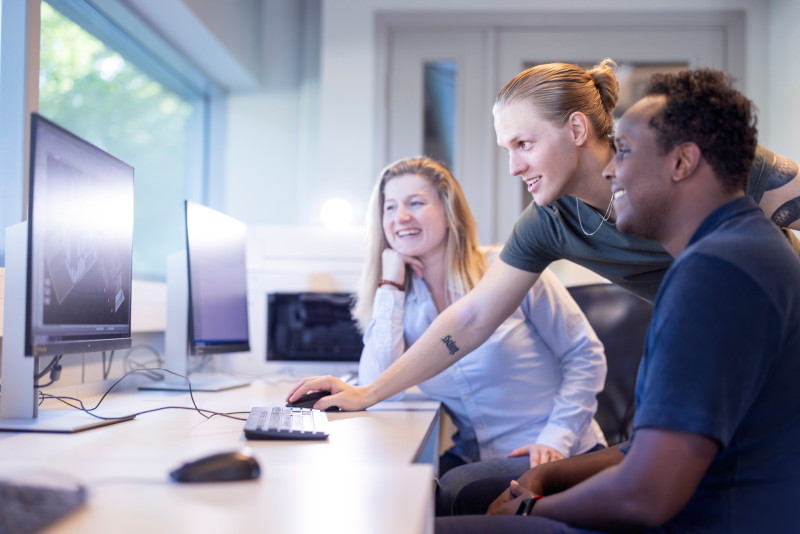 Tre studenter jobber sammen foran en PC-skjerm med byggtegninger.