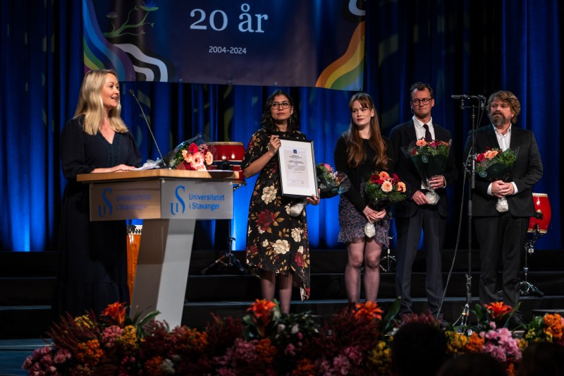 En gruppe mennesker på en scene med diplomer i hendene.