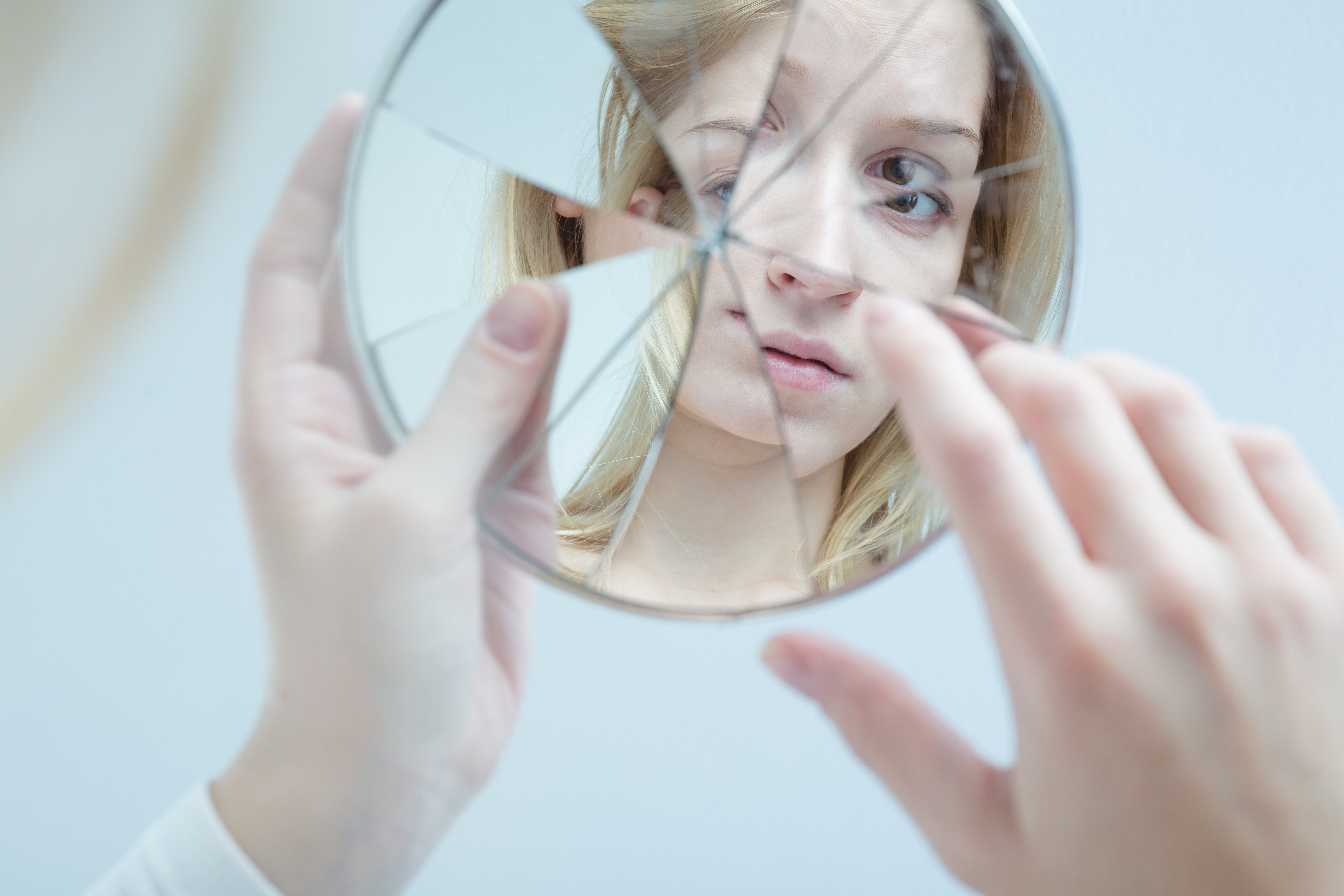 Speilbilde av en ung dame i et sprukket speil