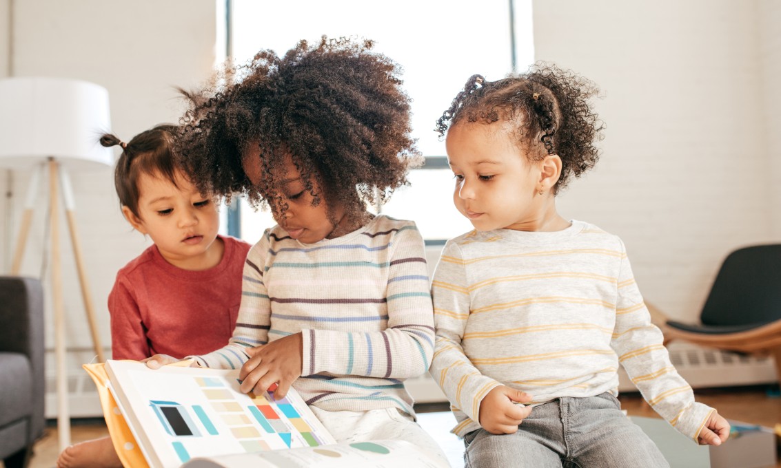 Tre små barn leser sammen i en bildebok