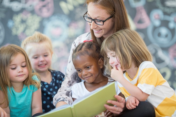 barnehagelærer med barn leser bøker