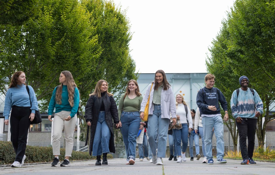 10 studenter gående ute på campus i fint vær.